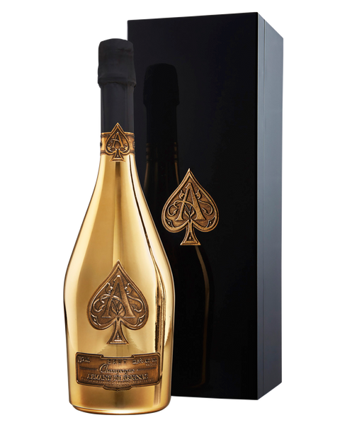 A gold champagne bottle with a black spade emblem, standing next to a tall black gift box with a matching spade design.